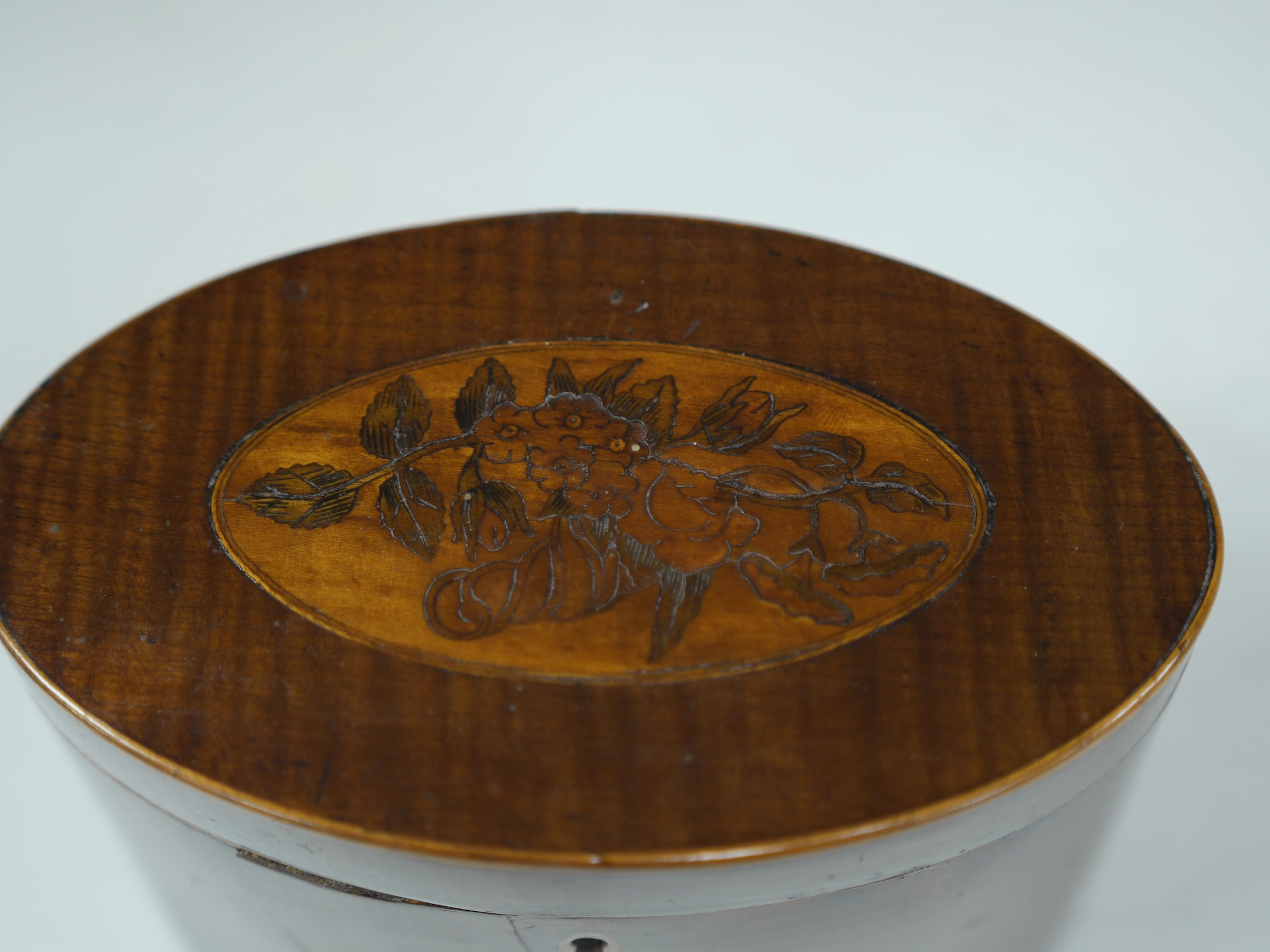 A George III oval inlaid sycamore tea caddy, 12cm high x 15cm wide. Condition - two splits to front.